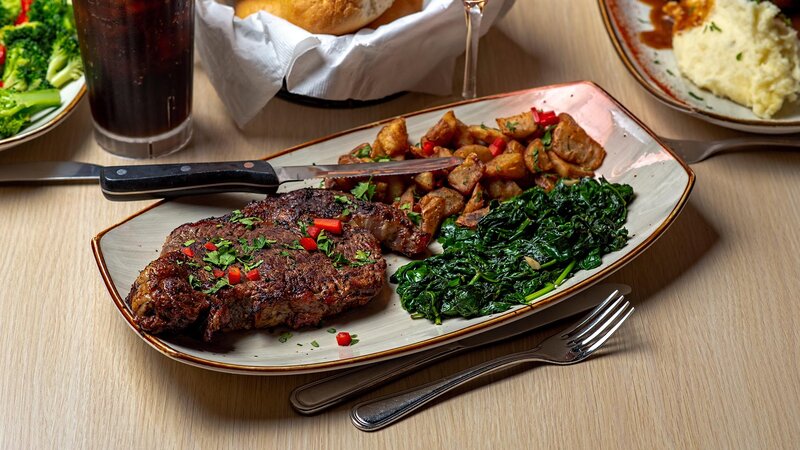 Steak entree with side of fried potatoes and spinach
